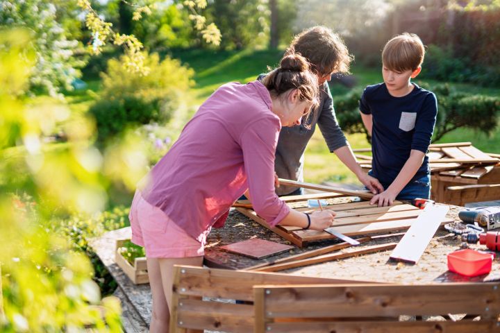 Man erkennt eine Familie, die gerade an Holz arbeitet.