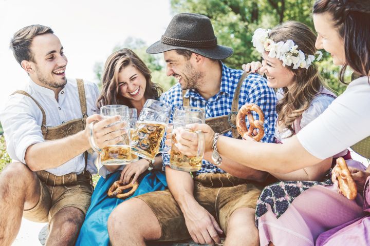 Man erkennt Freunde in Trachtenmode. Sie essen Brezel und trinken Bier.