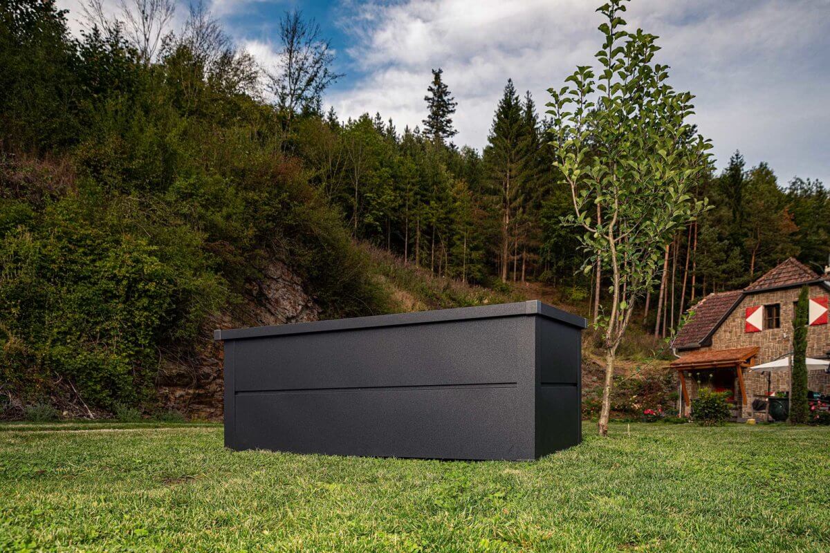 ILESTO Gartenbox in der Farbe anthrazit auf einem Grundstück vor einem alten Backsteinhaus