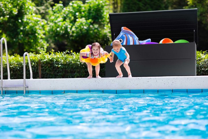 Man erkennt zwei Kinder, die ins Pool hüpfen.