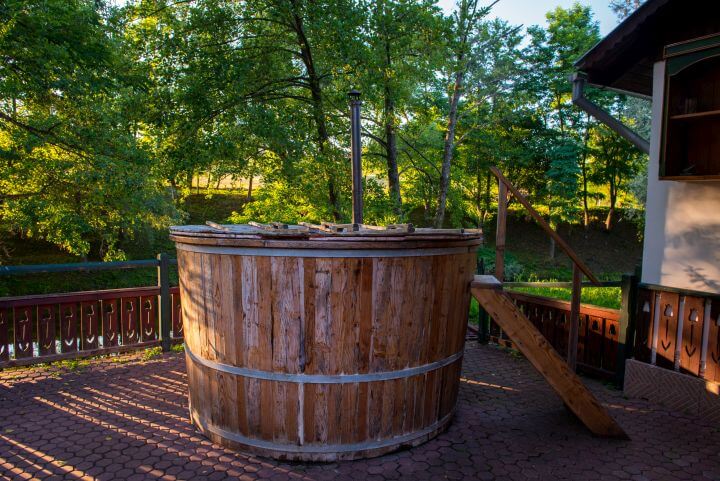 Badebottich aus Holz auf Terrasse mit Holzboden, dahinter grüne Bäume