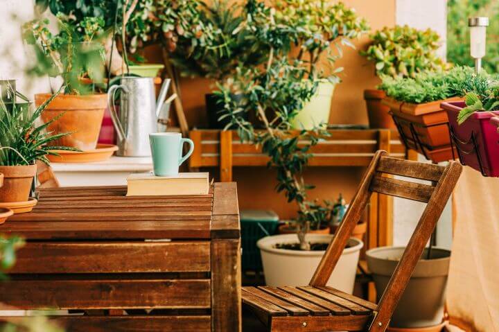 Balkon mit Holzmöbeln und Pflanzen in verschiedenen Blumentöpfen