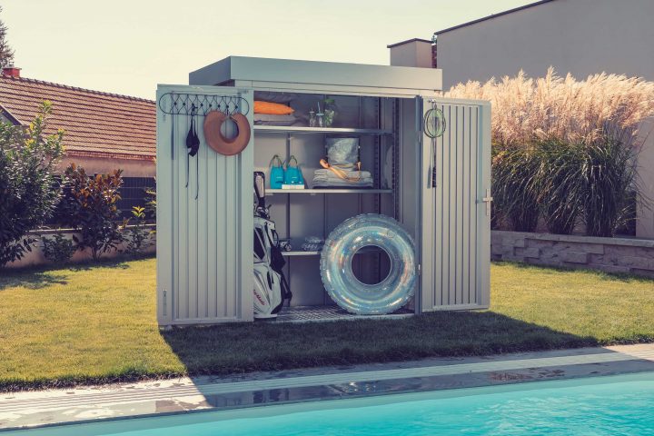 Man erkennt eine ILESTO Gartenhütte und ein Pool.