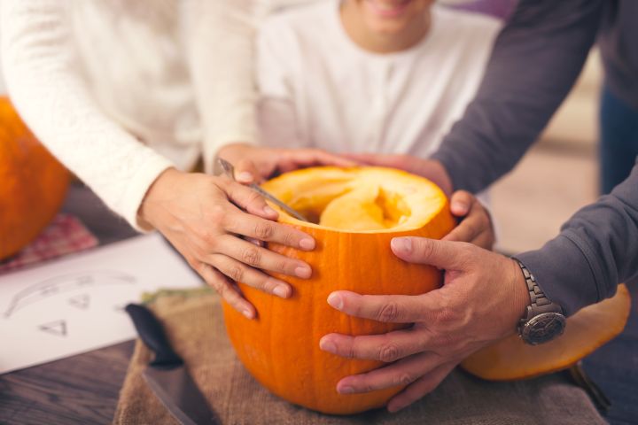 Familie hölt Kürbis aus um daraus Kürbislaternen als Herbstdeko zu basteln