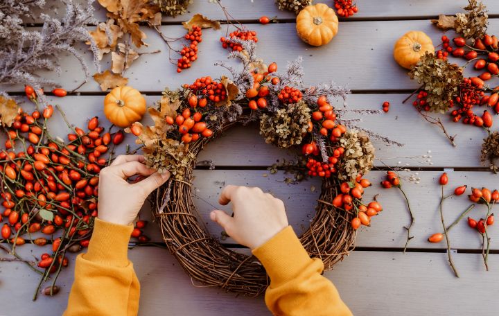 Frau bastelt Herbstkranz mit Laub als Herbstdeko