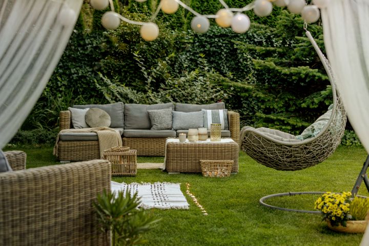 Eine Gartenlounge aus Rattan, ein Hägensessel und eine Lichterkette für moderne Gartengestaltung