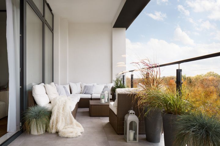 Schöner Balkon mit Korbmöbeln und weißen Kissen an einem schönen Herbsttag