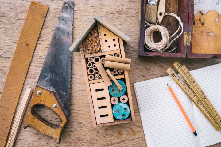 Insektenhotel nicht fertig neben einer Säge und Handwerkzeug auf einem großen Holztisch