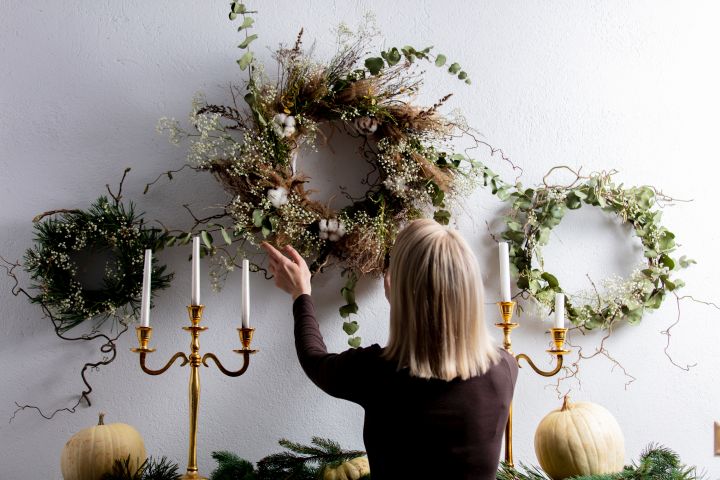 Frau hängt Weihnachtskranz auf