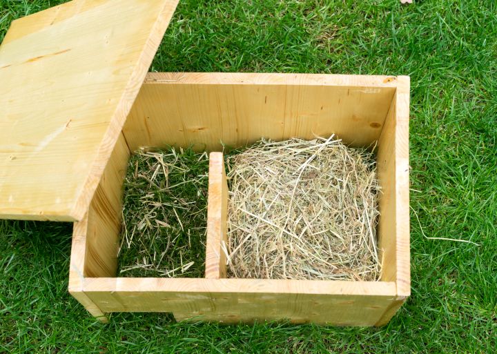 Selbstgemachtes Igelhaus mit offenem Dach und gefüllt mit Heu und Gras. Ansicht von oben