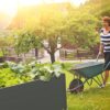 modernes hochbeet bpa-frei im garten mit frau und scheibtruhe