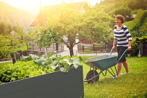 modernes hochbeet bpa-frei im garten mit frau und scheibtruhe